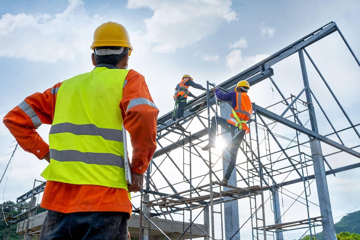 A San Juan College student watching two other students working on a steel frame for a building