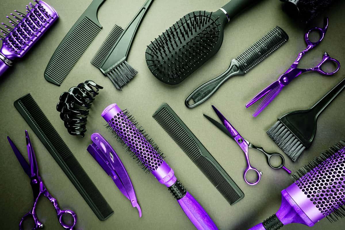 salon tools on a flat surface background, combs, brushes, scissors, curling irons.